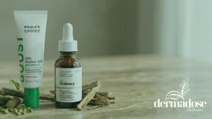 Paula's Choice 10% Azelaic Acid Booster y The Ordinary Salicylic Acid 2% junto a ramas de regaliz y semillas sobre mármol, comparativa de ácido azeláico y salicílico para el acné