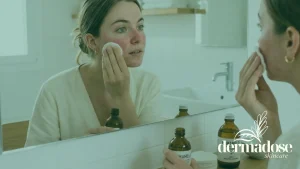 Mujer con rosácea aplicando tónico de hamamelis con algodón en la mejilla frente al espejo del baño