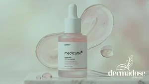 Medicube PDRN Pink Peptide Serum frasco rosado con textura gel sobre superficie de mármol con gotas de sérum