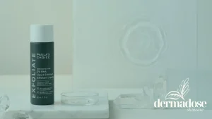 Paula's Choice Skin Perfecting 2% BHA Liquid Exfoliant botella verde oscura sobre superficie de mármol con cristales y placa de Petri